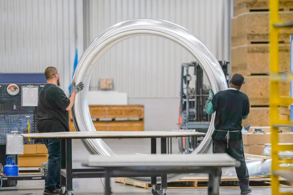 Two Employees handling a large metal lipskin